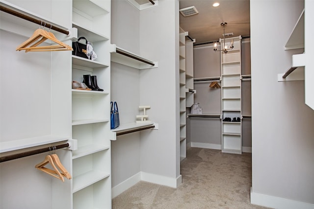 walk in closet with a chandelier and light carpet