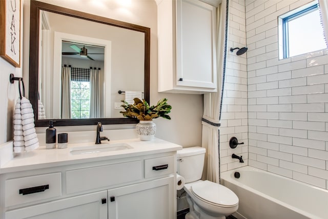 full bathroom with tiled shower / bath, toilet, ceiling fan, and vanity with extensive cabinet space