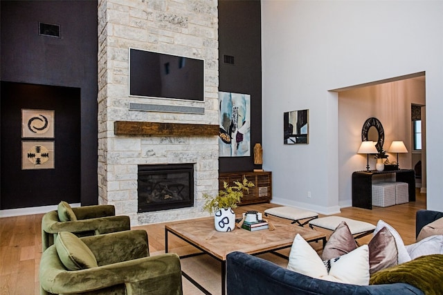 living room with light hardwood / wood-style floors, a fireplace, and a high ceiling