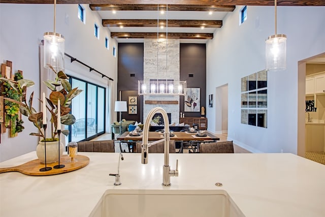 kitchen featuring pendant lighting, sink, a towering ceiling, and beamed ceiling