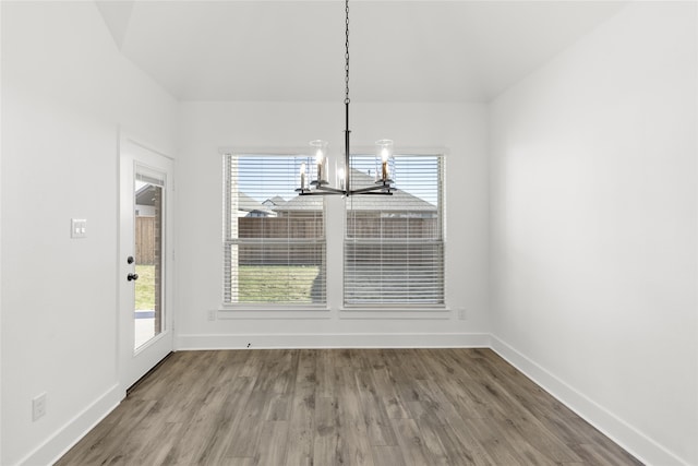 unfurnished dining area with hardwood / wood-style flooring and a chandelier