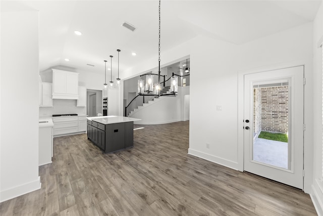 kitchen featuring white cabinetry, a chandelier, a kitchen island, hanging light fixtures, and hardwood / wood-style floors