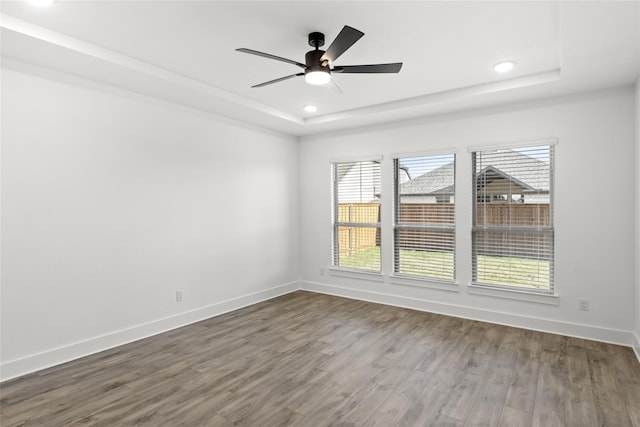 spare room with a tray ceiling, wood-type flooring, and ceiling fan