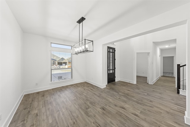 unfurnished dining area featuring a notable chandelier and wood-type flooring