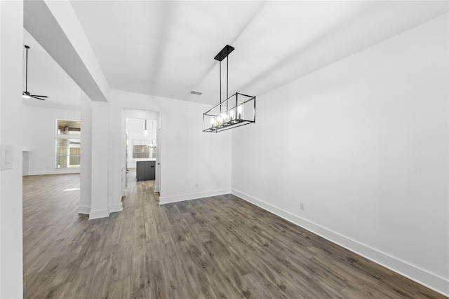 unfurnished dining area with dark hardwood / wood-style floors and ceiling fan with notable chandelier