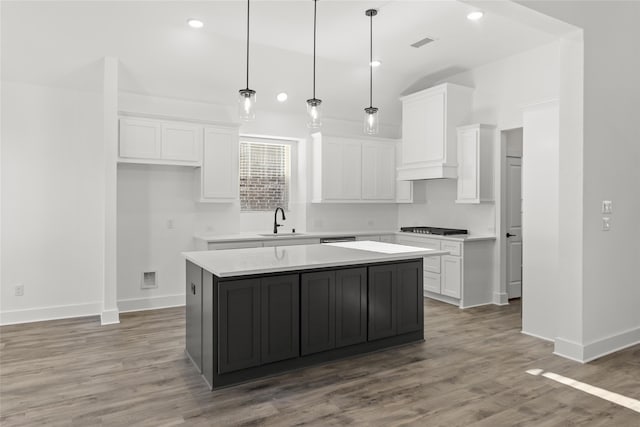 kitchen featuring white cabinets, hanging light fixtures, hardwood / wood-style floors, and a kitchen island