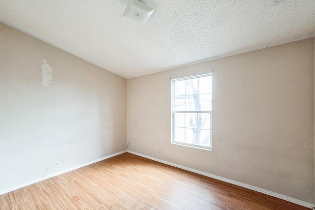 empty room with light hardwood / wood-style floors and a textured ceiling