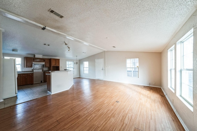 unfurnished living room with hardwood / wood-style flooring, vaulted ceiling, and a textured ceiling