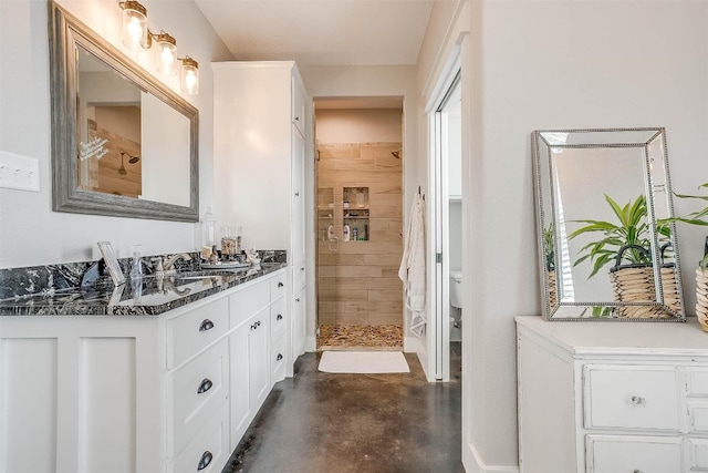 bathroom with toilet, a shower, vanity, and concrete floors