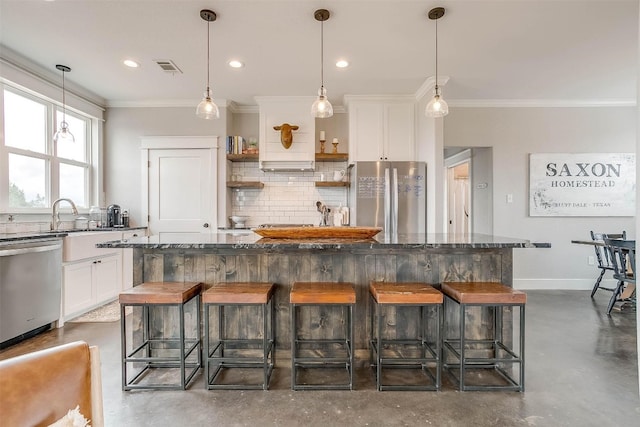 kitchen with white cabinets, a center island, a kitchen bar, and appliances with stainless steel finishes