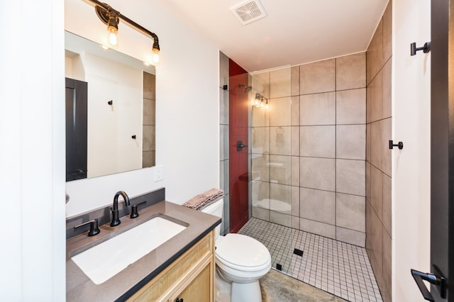 bathroom featuring tile patterned floors, toilet, vanity, and a tile shower