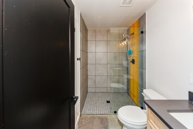 bathroom featuring vanity, tiled shower, and toilet