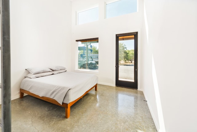 bedroom with a high ceiling, access to outside, and concrete floors