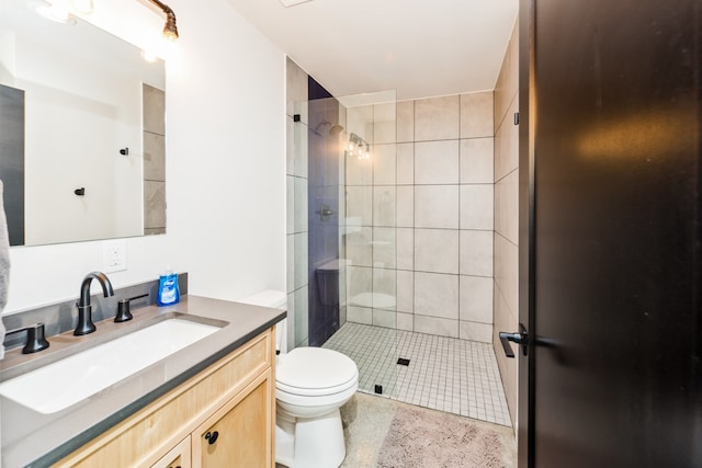 bathroom featuring tiled shower, vanity, and toilet