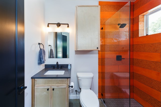 bathroom featuring vanity, tile patterned flooring, a tile shower, and toilet