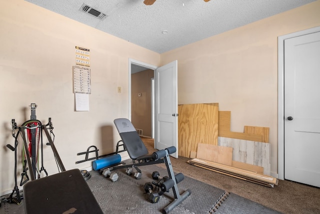 workout area featuring ceiling fan, carpet flooring, and a textured ceiling