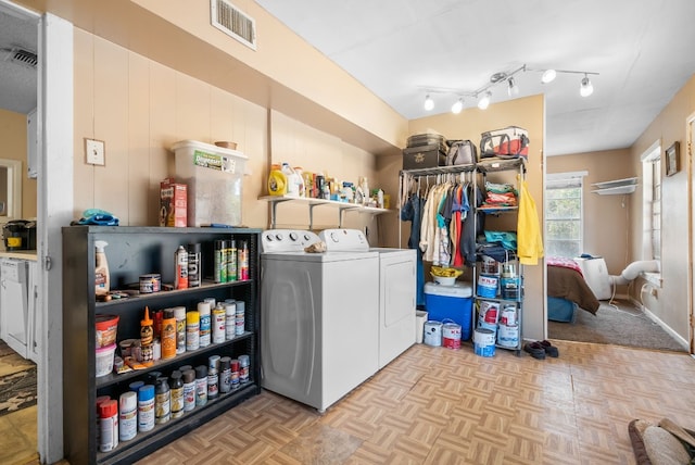 clothes washing area with rail lighting, separate washer and dryer, and light parquet flooring