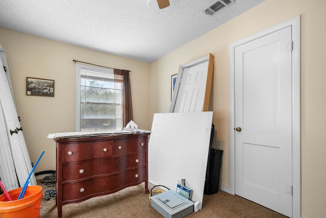 interior space with a textured ceiling, ceiling fan, and dark colored carpet