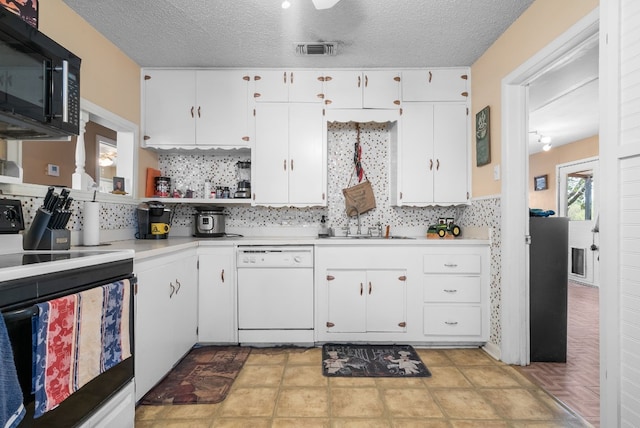 kitchen with electric stove, tasteful backsplash, dishwasher, and white cabinetry