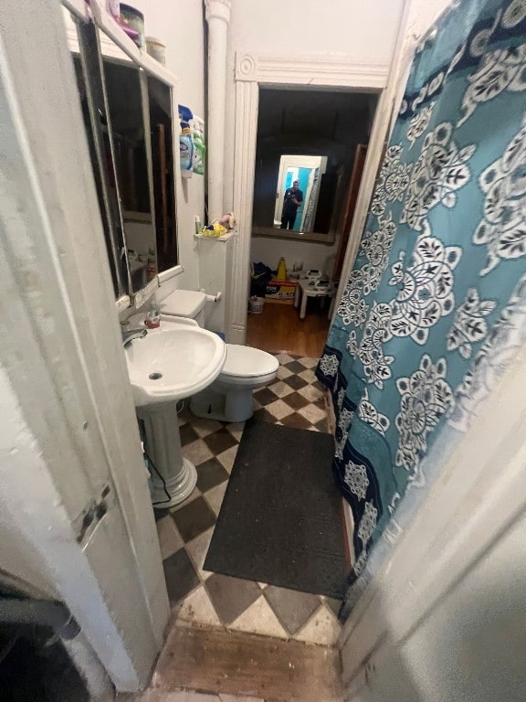 bathroom with toilet, tile flooring, and sink