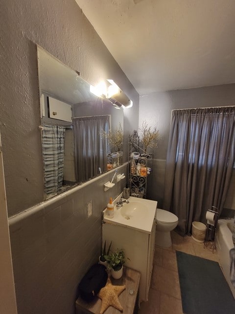 bathroom featuring toilet, tile walls, tile flooring, and vanity with extensive cabinet space