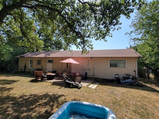 back of property with an outdoor fire pit, a patio area, and a lawn