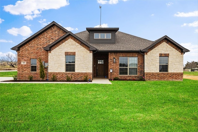 view of front of home with a front lawn, brick siding, stone siding, and roof with shingles