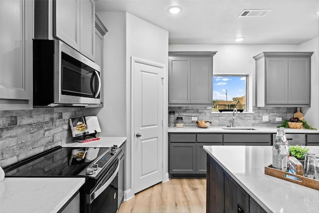 kitchen featuring sink, gray cabinetry, backsplash, electric range, and light hardwood / wood-style flooring