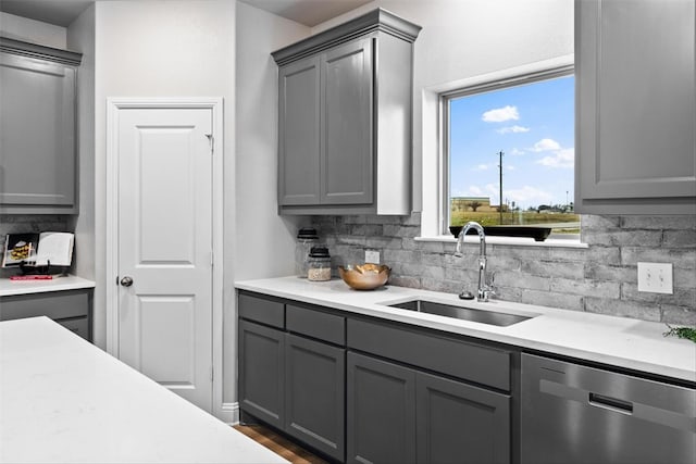 kitchen featuring dishwasher, gray cabinets, tasteful backsplash, and sink