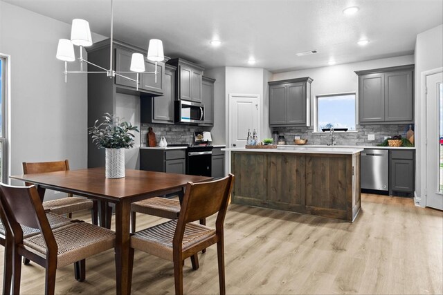 kitchen featuring sink, light hardwood / wood-style flooring, gray cabinets, a kitchen island, and appliances with stainless steel finishes