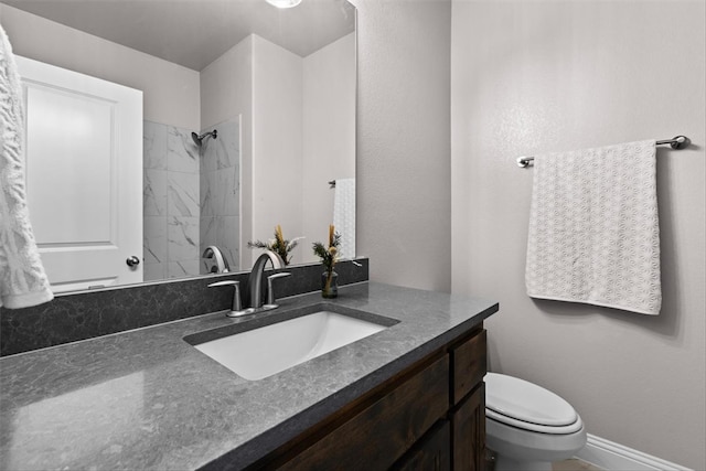 bathroom featuring vanity, toilet, and a tile shower