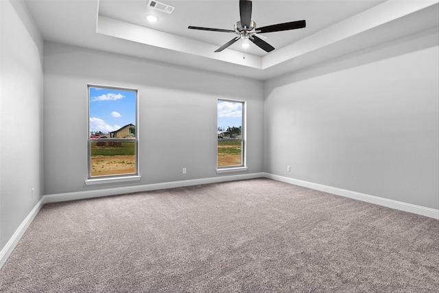 carpeted empty room featuring ceiling fan and a tray ceiling