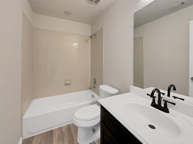 full bathroom with tiled shower / bath combo, vanity, hardwood / wood-style flooring, and toilet