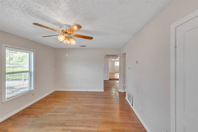 unfurnished room featuring light wood-type flooring, ceiling fan, and a textured ceiling