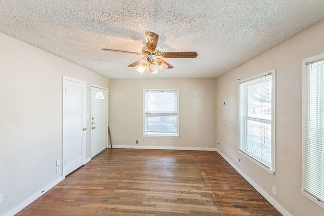 spare room with ceiling fan, a wealth of natural light, dark hardwood / wood-style floors, and a textured ceiling