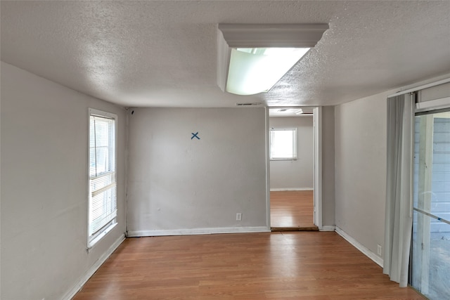 spare room with hardwood / wood-style flooring, a textured ceiling, and plenty of natural light