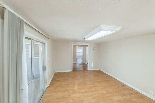 unfurnished room with a textured ceiling and light hardwood / wood-style flooring