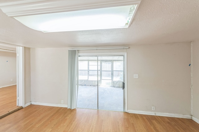 spare room with a textured ceiling and light wood-type flooring