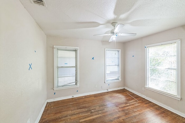 empty room featuring dark wood-type flooring, a textured ceiling, and ceiling fan