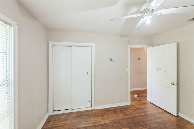 unfurnished bedroom with ceiling fan, dark hardwood / wood-style floors, and a closet