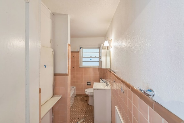 full bathroom with tile walls, toilet, vanity, and tile patterned flooring