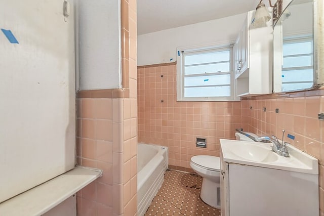 bathroom with vanity, toilet, a bath, and tile walls