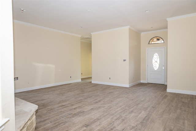 entryway with light wood finished floors, ornamental molding, and baseboards