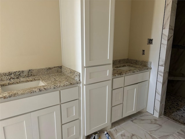 bathroom featuring walk in shower, two vanities, a sink, and marble finish floor