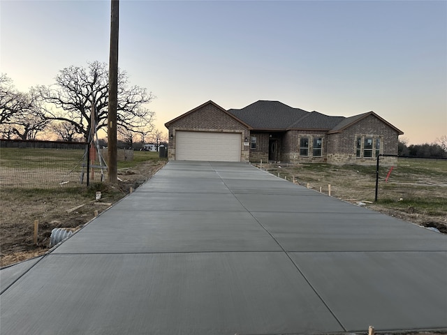 single story home featuring a garage, brick siding, driveway, and a yard