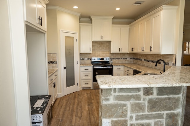 kitchen featuring range with electric cooktop, ornamental molding, a sink, visible vents, and a peninsula