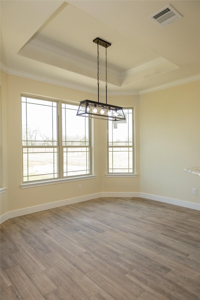spare room featuring crown molding, visible vents, wood finished floors, and a raised ceiling