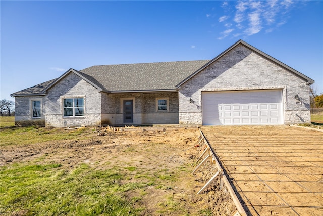 view of front of property with brick siding, an attached garage, and roof with shingles