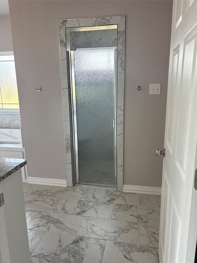 bathroom featuring marble finish floor, a stall shower, vanity, and baseboards