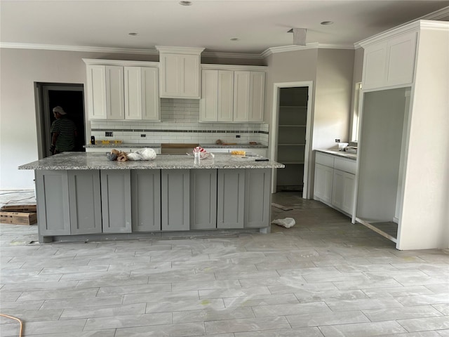 kitchen with ornamental molding, backsplash, and a center island